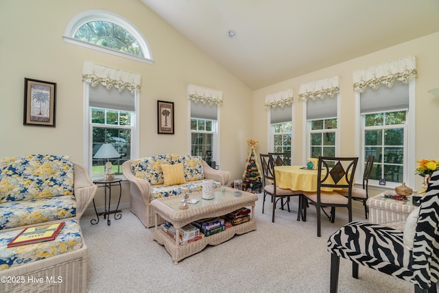 carpeted living room featuring baseboards and high vaulted ceiling