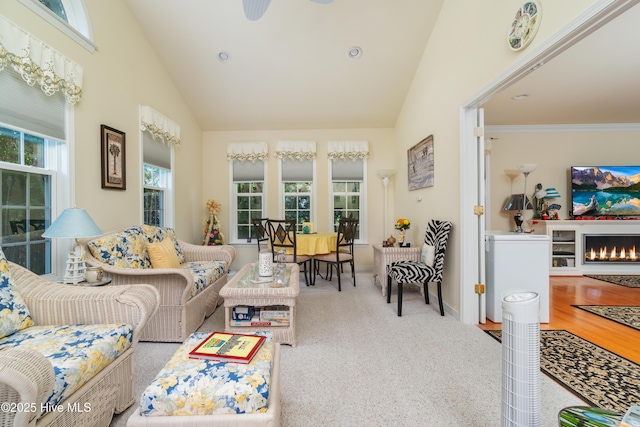 living area with vaulted ceiling, carpet flooring, baseboards, and a lit fireplace