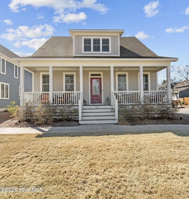 bungalow-style home with covered porch, a front lawn, and roof with shingles