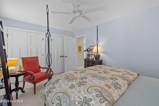 bedroom with carpet floors, ceiling fan, and two closets