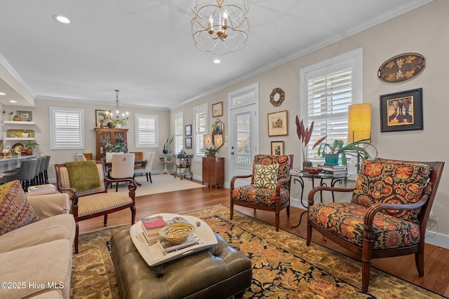 living room with crown molding, baseboards, a notable chandelier, and wood finished floors