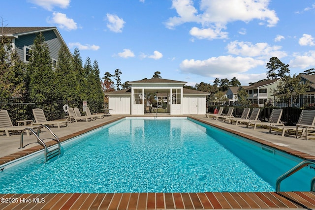 community pool featuring fence, an outbuilding, a patio, and an exterior structure