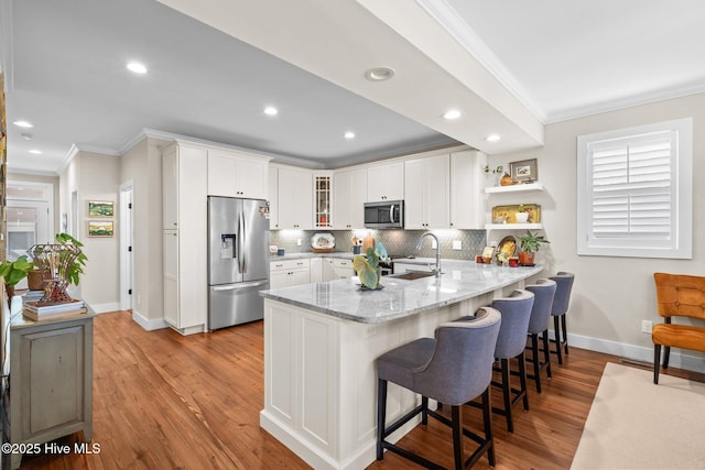 kitchen featuring a peninsula, appliances with stainless steel finishes, a sink, and crown molding