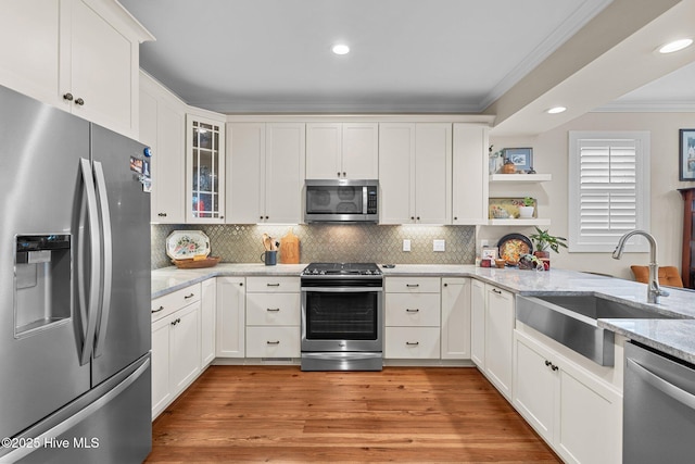 kitchen with open shelves, stainless steel appliances, decorative backsplash, ornamental molding, and a sink