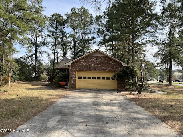 view of side of property with an attached garage, brick siding, and driveway