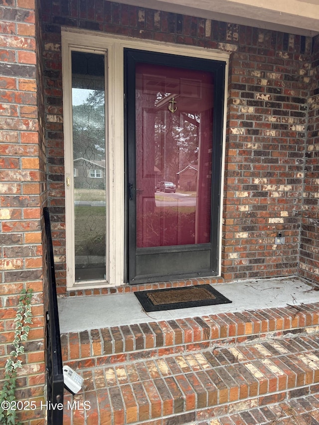 view of exterior entry featuring brick siding