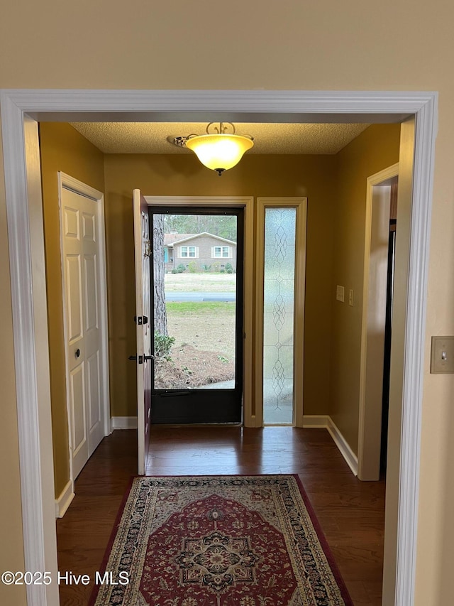 entryway with baseboards, dark wood-style flooring, and a textured ceiling