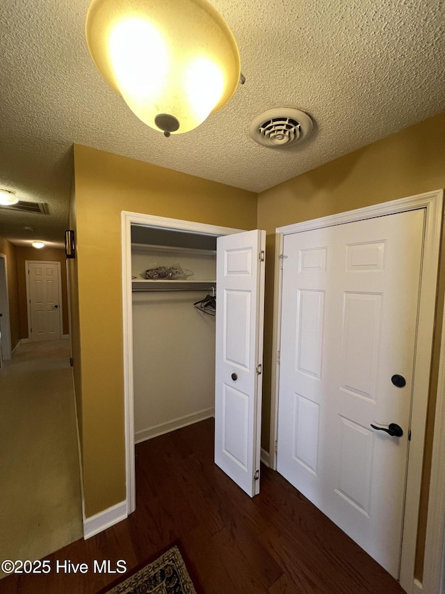 unfurnished bedroom featuring visible vents, a textured ceiling, a closet, and wood finished floors