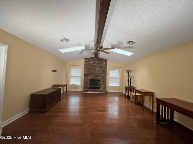 unfurnished living room with visible vents, vaulted ceiling with skylight, dark wood-type flooring, and a ceiling fan