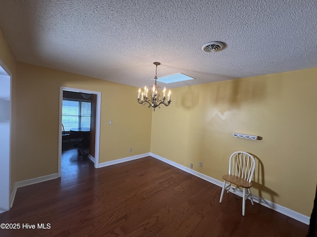 unfurnished dining area featuring a notable chandelier, visible vents, baseboards, and dark wood-style floors