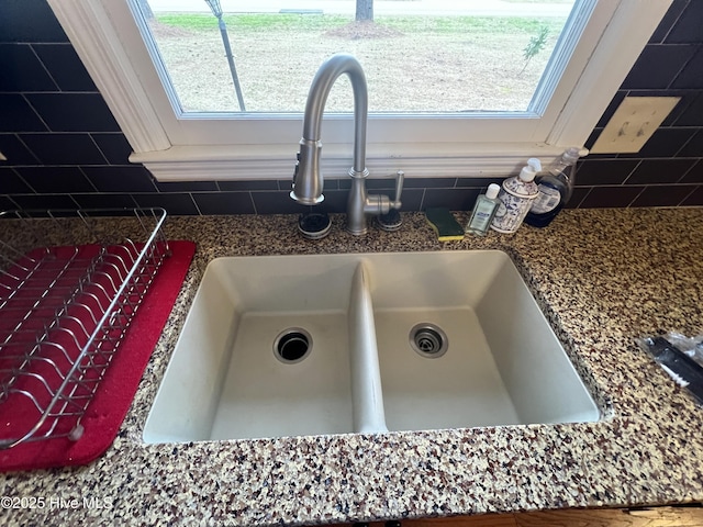 room details featuring a sink, backsplash, and dark countertops