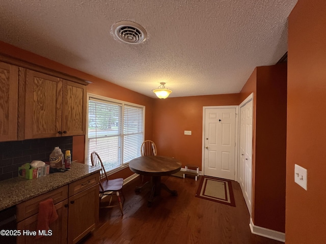 dining room featuring visible vents, baseboards, a textured ceiling, and dark wood-style flooring