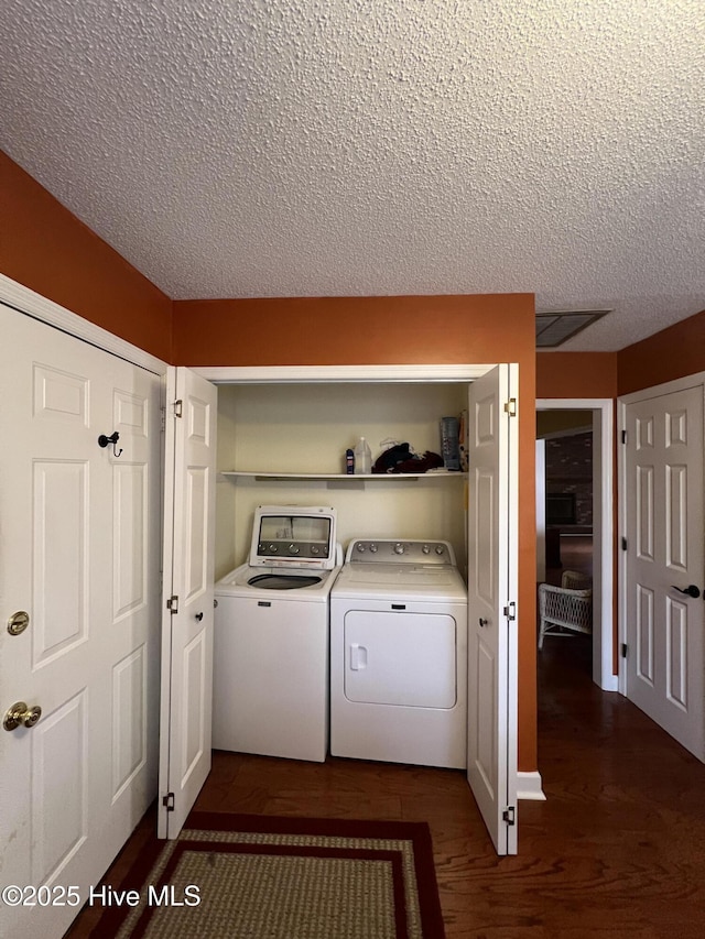 laundry room featuring laundry area, separate washer and dryer, dark wood-style flooring, and a textured ceiling