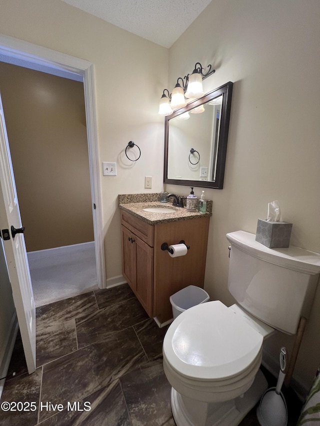 bathroom with baseboards, a textured ceiling, vanity, and toilet