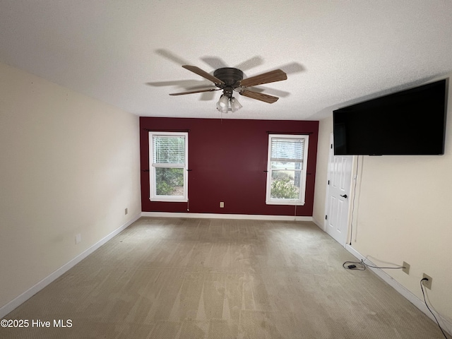 unfurnished living room with light colored carpet, a textured ceiling, baseboards, and a ceiling fan