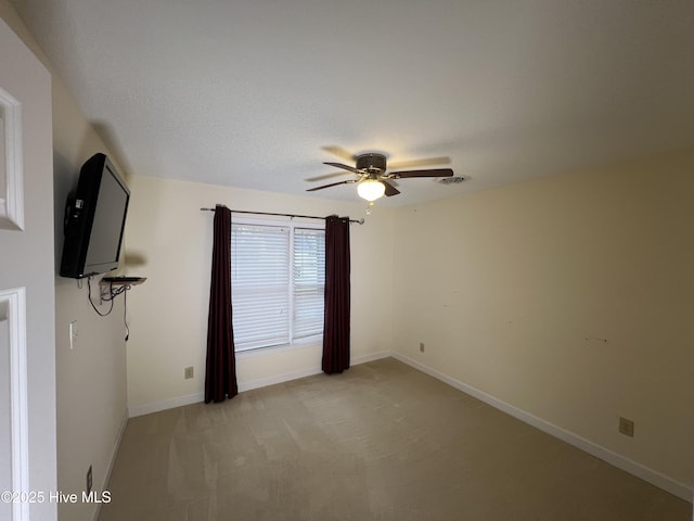 empty room featuring light carpet, visible vents, baseboards, and ceiling fan