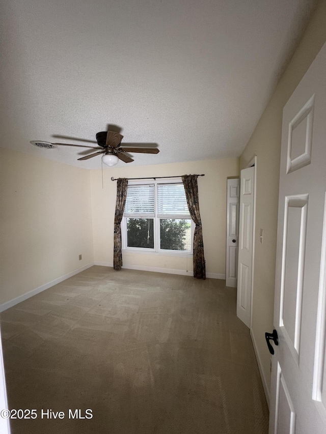 empty room with baseboards, a textured ceiling, light carpet, and ceiling fan