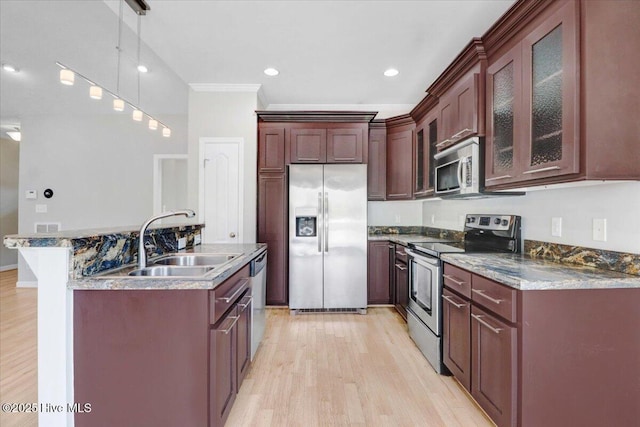 kitchen featuring a center island with sink, light wood-style flooring, glass insert cabinets, stainless steel appliances, and a sink