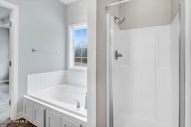 full bath featuring a stall shower, a garden tub, and baseboards