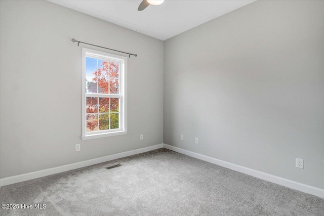 carpeted spare room with ceiling fan, visible vents, and baseboards