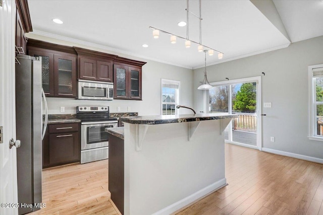 kitchen with appliances with stainless steel finishes, dark brown cabinetry, light wood-style floors, and a breakfast bar area