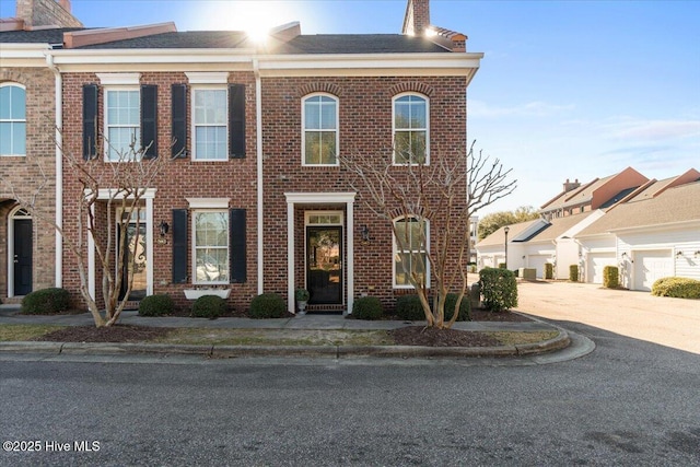 townhome / multi-family property featuring concrete driveway, brick siding, and a chimney