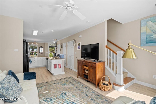 living area featuring ceiling fan, baseboards, stairs, ornamental molding, and light wood finished floors