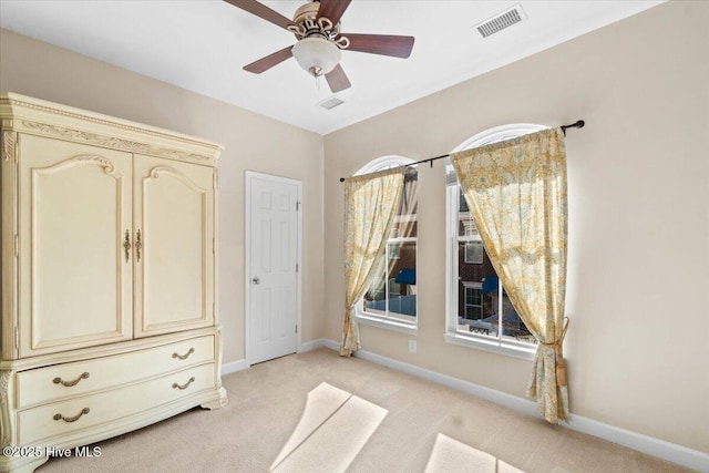 unfurnished bedroom with a ceiling fan, visible vents, light carpet, and baseboards