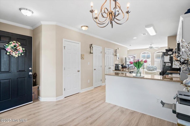 kitchen featuring light stone counters, crown molding, light wood-style flooring, white cabinetry, and a peninsula