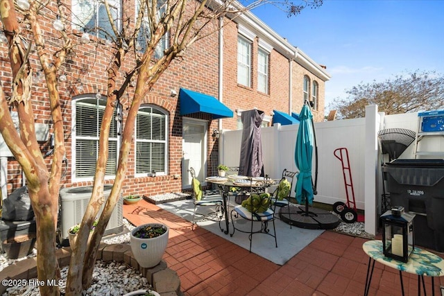 view of patio with fence, central AC unit, and outdoor dining area