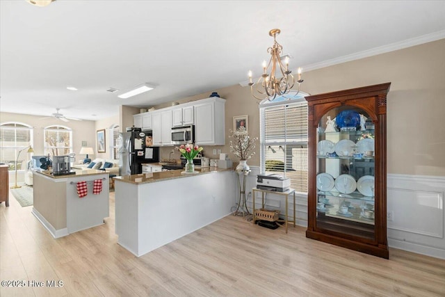 kitchen with stainless steel microwave, light wood-style flooring, freestanding refrigerator, white cabinetry, and a peninsula