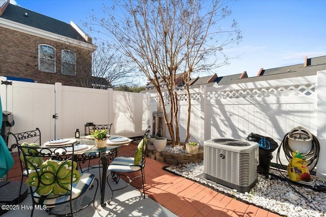 view of patio / terrace with a fenced backyard, central AC, and outdoor dining space