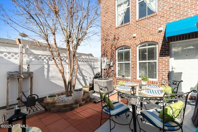 view of patio / terrace featuring outdoor dining space, fence, and central AC unit