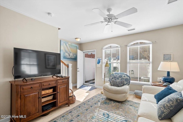 living room featuring light wood-style floors, visible vents, baseboards, and a ceiling fan