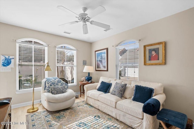 living room with baseboards, ceiling fan, visible vents, and wood finished floors