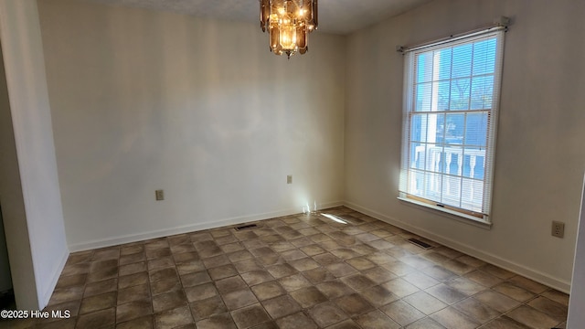 spare room with plenty of natural light, a chandelier, and baseboards