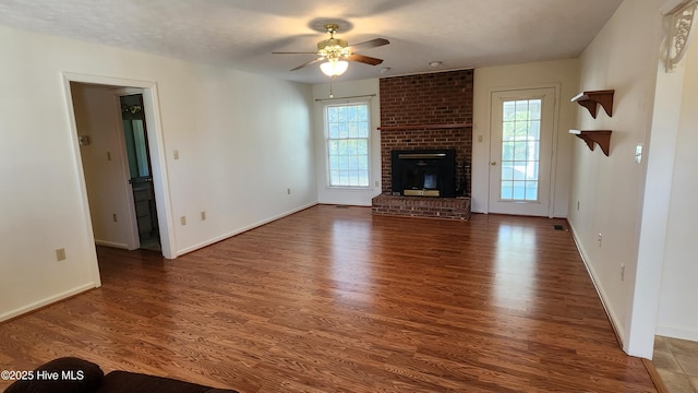 unfurnished living room featuring a brick fireplace, baseboards, a ceiling fan, and wood finished floors