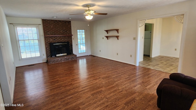 unfurnished living room featuring a fireplace, visible vents, ceiling fan, wood finished floors, and baseboards