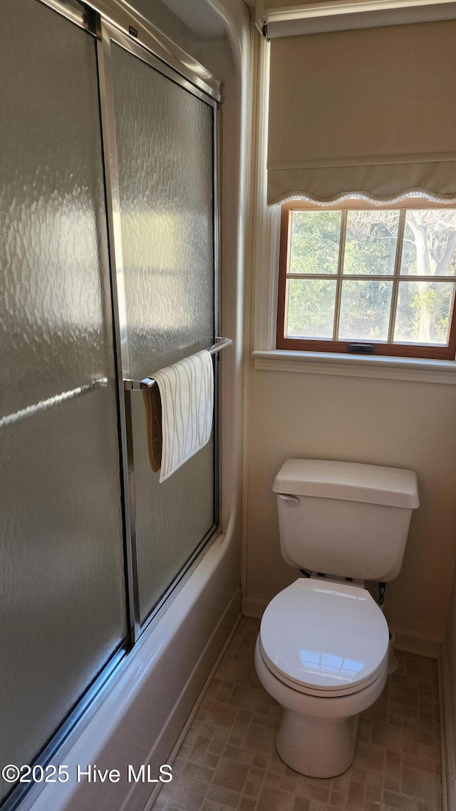 full bathroom featuring enclosed tub / shower combo, toilet, and baseboards