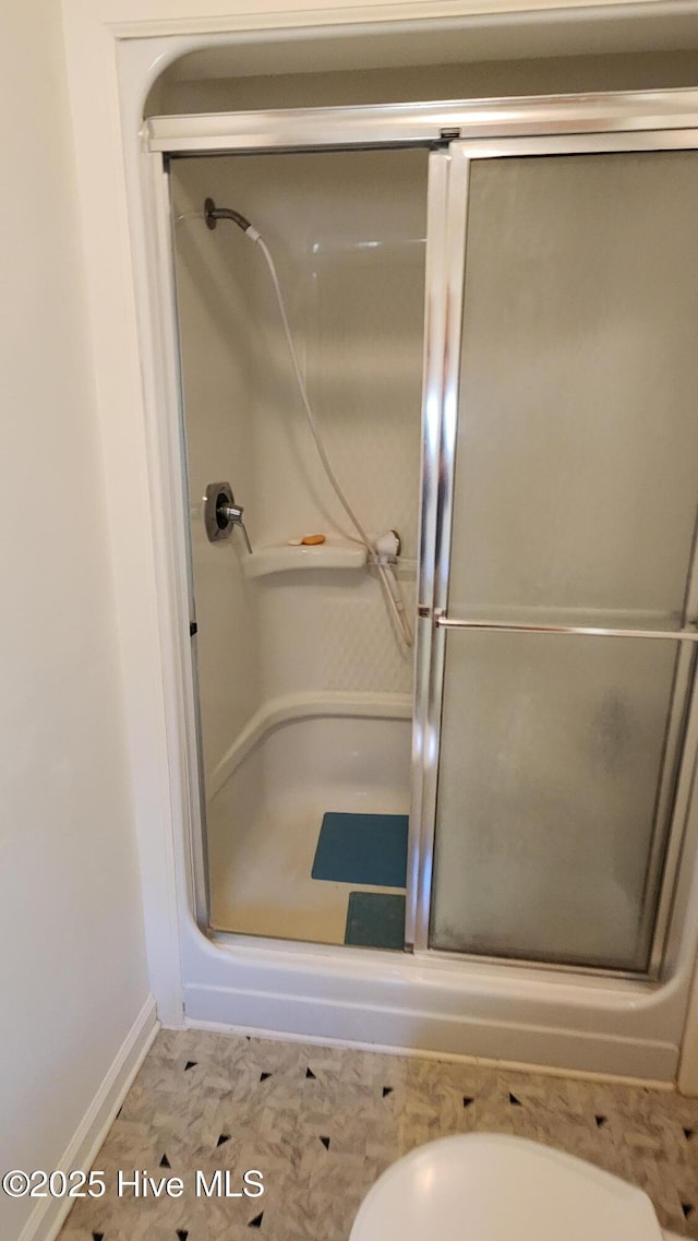 bathroom featuring toilet and a shower stall