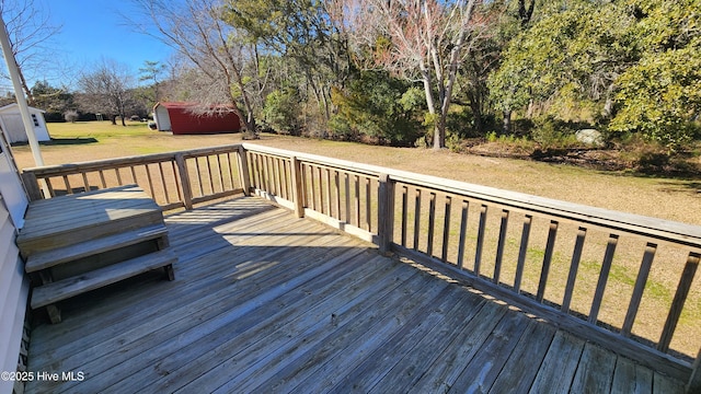 deck featuring a storage shed, a yard, and an outbuilding