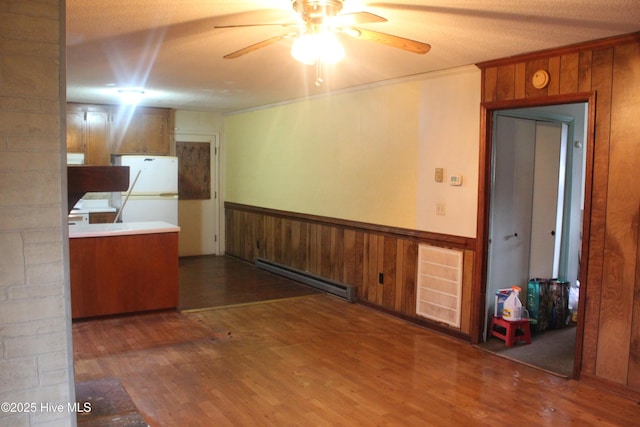 kitchen featuring a wainscoted wall, a baseboard radiator, ornamental molding, freestanding refrigerator, and wood finished floors