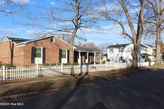 view of front of home featuring a fenced front yard, a residential view, and brick siding