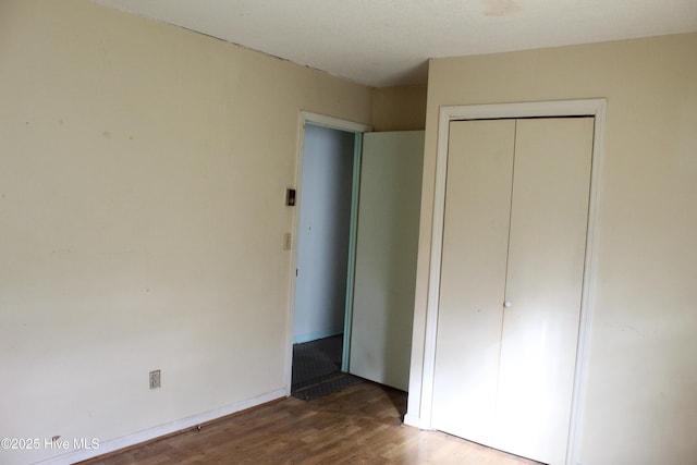 unfurnished bedroom featuring a closet, wood finished floors, and baseboards