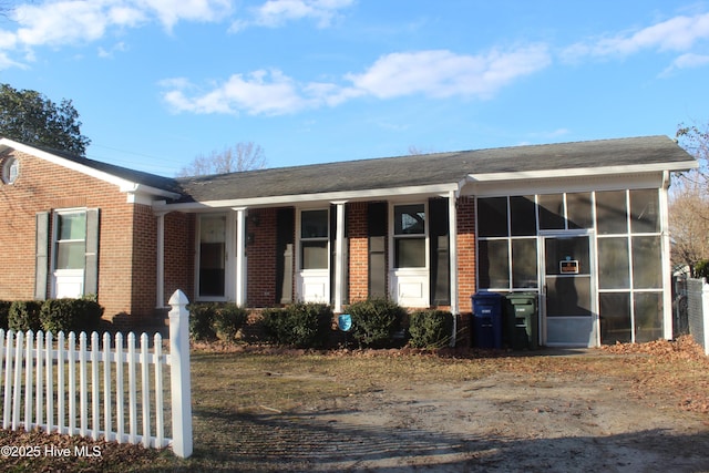 view of front of home featuring brick siding and a sunroom