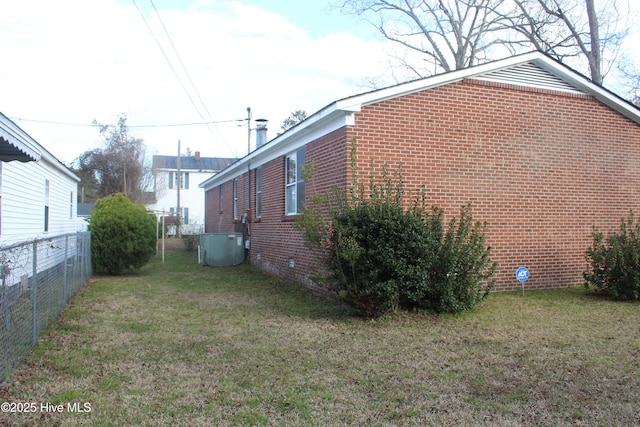 view of side of property featuring central air condition unit, brick siding, fence, a yard, and crawl space