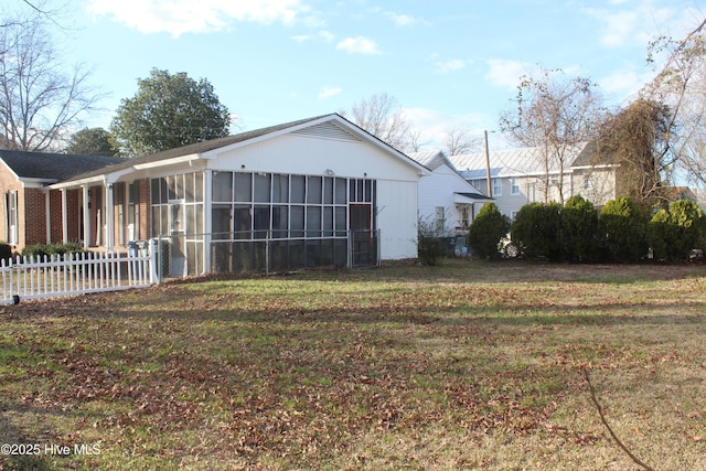 rear view of house featuring a sunroom, fence, and a yard