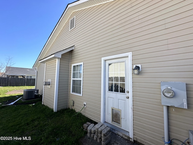 rear view of property featuring a lawn, cooling unit, and fence