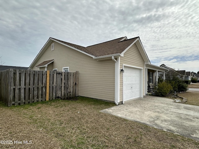 view of side of property featuring a garage, roof with shingles, fence, and driveway