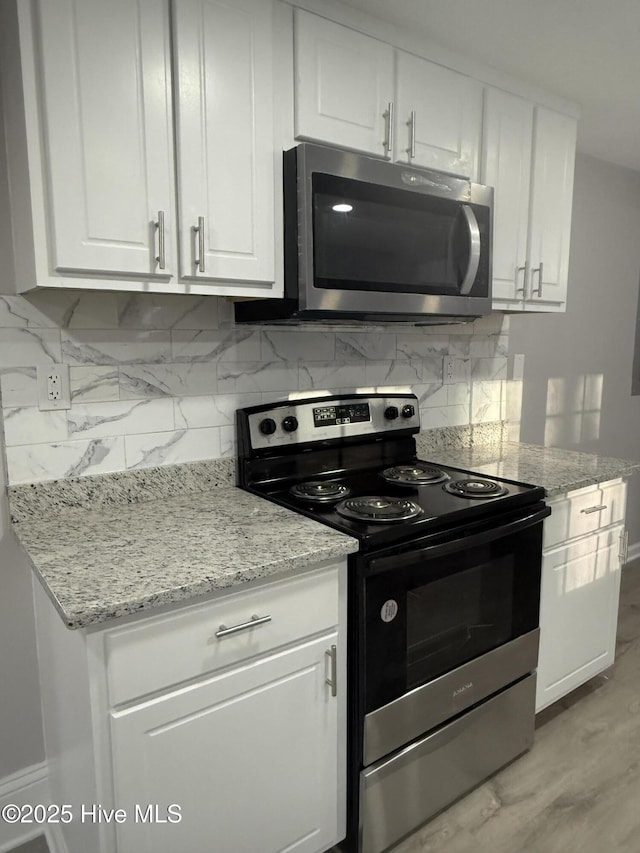 kitchen featuring white cabinets, light stone countertops, tasteful backsplash, and stainless steel appliances